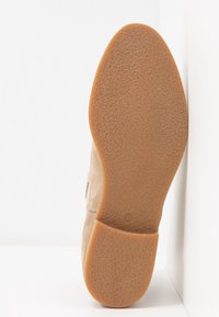 Semelle d'une chaussure en daim beige avec une semelle extérieure en caoutchouc texturée de couleur marron clair et un petit marquage de taille "37" près du talon.