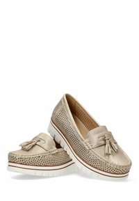 Mocasines beige perforados con un acento de borlas, que presentan una suela gruesa blanca con una sutil raya marrón. Textura suave y forma redondeada.
