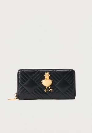 Cartera negra de cuero acolchado con cremallera que presenta un emblema dorado de rana con corona centrado en el frente.