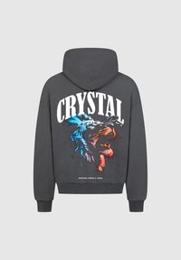 Felpa grigia con cappuccio e cordino, con una grafica colorata di un leone e la scritta "CRYSTAL PARIS" sul retro. Tessuto morbido, polsini a costine e orlo.