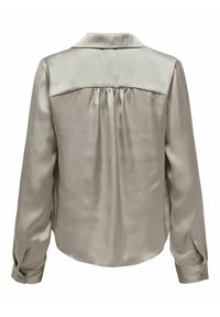 Blouse en satin gris clair avec une texture lisse, des poignets à boutons, des plis au dos et un col structuré. Le design présente un style épuré et minimaliste.
