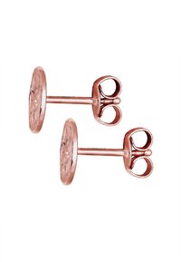 Orecchini in metallo color oro rosa con una base circolare dalla superficie texture e dettagli a forma di fiocco sui perni.