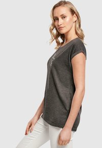 Grå T-shirt med korte ærmer lavet af blødt stof, med en rund halsudskæring og et minimalistisk hvidt linjemønster på forsiden.