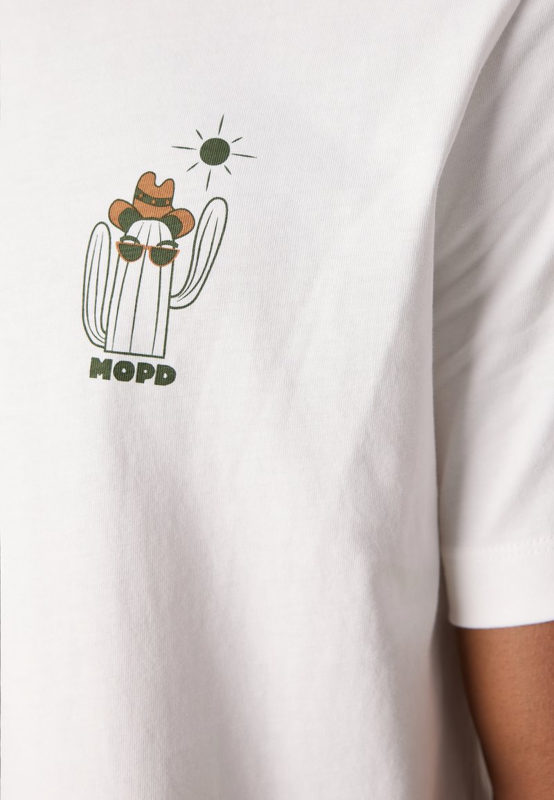Weißes Baumwoll-T-Shirt mit einem Kaktus-Motiv, der eine Sonnenbrille und einen Cowboy-Hut trägt, begleitet von einer Sonne und dem Text "MOPD" in grün.