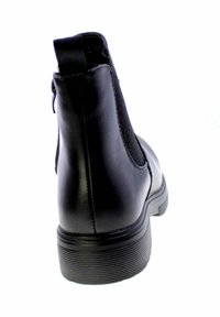 Stivaletto in pelle nera con suola spessa e rigata, pannello laterale elastico e linguetta sul retro, mostrato da dietro.
