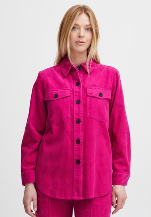 Bright pink corduroy shirt with a collar, front button closure, two chest pockets, and long sleeves featuring buttoned cuffs.