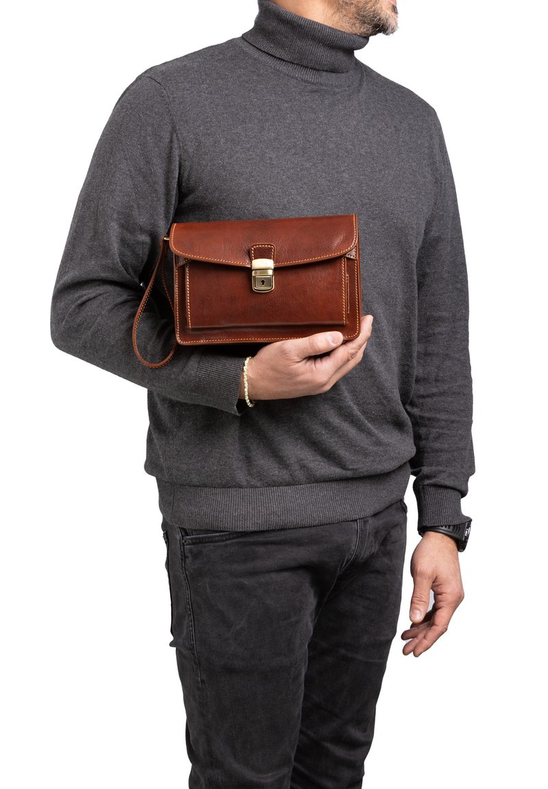 Borsa a tracolla in pelle marrone con pattina, chiusura in oro e tracolla removibile. Presenta bordi cuciti e forma rettangolare, tenuta da una persona.