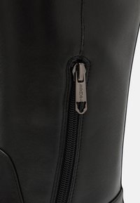 Botas de cuero negro con cremallera lateral, acabado texturizado y una silueta elegante. El tirador de la cremallera tiene grabado "MARCIN".