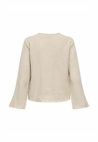 Hellbeige, strukturiertes Langarmoberteil mit rundem Ausschnitt und ausladenden Ärmeln. Die Vorderseite ist glatt und weist ein dezentes, gewelltes Muster auf.