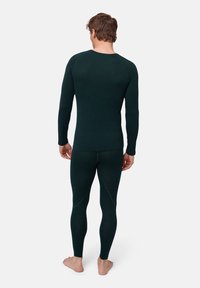 Mörkgrön thermotröja med långa ärmar och matchande leggings, har sömdetaljer och en texturerad tygkvalitet, lämplig för lager-på-lager.