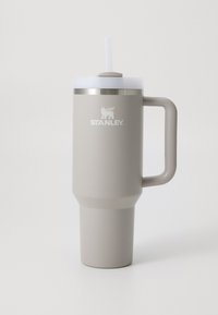 Stainless steel travel mug in beige with a wide handle, a screw-on lid, and a straw. Features a logo and a textured finish.