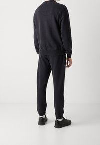 Sudadera gris oscuro y joggers a juego hechos de algodón, con puños y tobillos acanalados, de corte relajado y con detalles de diseño mínimos.