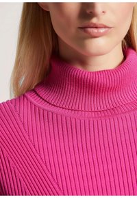 Eng anliegender, gerippter Pullover in leuchtendem Pink mit hohem Kragen, der vertikale und diagonale Linien für Textur und stilistische Details aufweist.