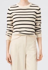 Sweter w paski w kremowym i czarnym kolorze, wykonany z dzianiny, z okrągłym dekoltem, ściągaczami przy mankietach oraz lekko skróconym dołem z bocznymi rozcięciami.