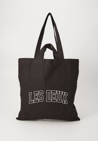 Black canvas tote bag with two sturdy handles, features white text reading "LES DEUX" on the front, smooth texture, rectangular shape.