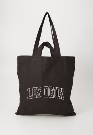 Saco tote preto em canvas com duas alças robustas, apresenta texto branco a dizer "LES DEUX" na frente, textura suave, forma retangular.