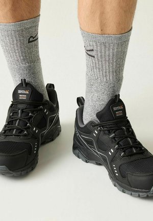 Czarne wodoodporne buty trekkingowe Black Regatta noszone z szarymi skarpetami do kostki na gołych nogach, pokazane z przodu i nieco z góry.