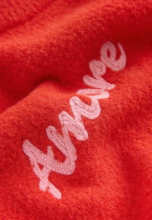 Red fabric with a soft, fuzzy texture featuring embroidered text in light pink. The design has a playful, cursive style.