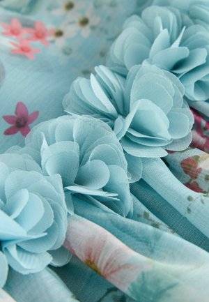Light blue fabric featuring layered flower appliqués with a textured floral print in pink and green, creating a soft, layered appearance.