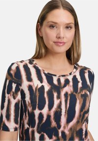 Koszulka z krótkim rękawem w kolorze granatowym z różowym wzorem w panterkę, z okrągłym dekoltem i gładką, miękką teksturą.