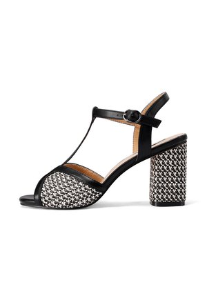 Sandali con tacco in bianco e nero con un motivo intrecciato sulla punta e un tacco a blocco spesso. Presentano una cinghia regolabile alla caviglia.