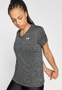 Maglietta sportiva grigia a maniche corte con scollo a V e una sottile texture mélange, con un logo bianco sul petto a sinistra.