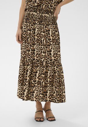 Femme portant une jupe midi imprimée léopard avec une taille smockée et un ourlet à volants, associée à des sandales à talons noires à lanières.