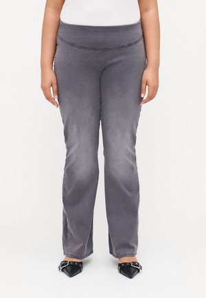Šedé, elastické kalhoty s vysokým pasem a hladkým povrchem. Vyznačují se slim fit střihem přes stehna, mírně se rozšiřují na kotnících.