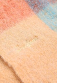Vilt sjaal in warme perziktinten met blauwe en oranje accenten, met een zachte textuur en geborduurd "Scalpers" logo in subtiel geel.