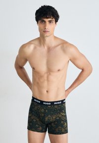 Hugo Herren Boxershorts in Dunkelgrün mit floralem Muster, schwarzer Bund mit "HUGO"-Logo, aus weichem, dehnbarem Stoff.