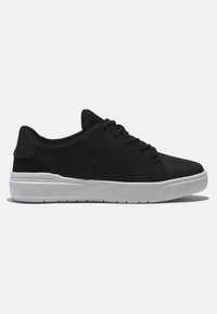 Black sneaker with a smooth, synthetic upper, white rubber sole, and contrasting black accents. Features a logo and six eyelets for laces.