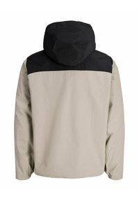 Veste à capuche avec une partie supérieure noire et une partie inférieure beige, fabriquée en matériau lisse et résistant à l'eau, avec des poignets élastiques.