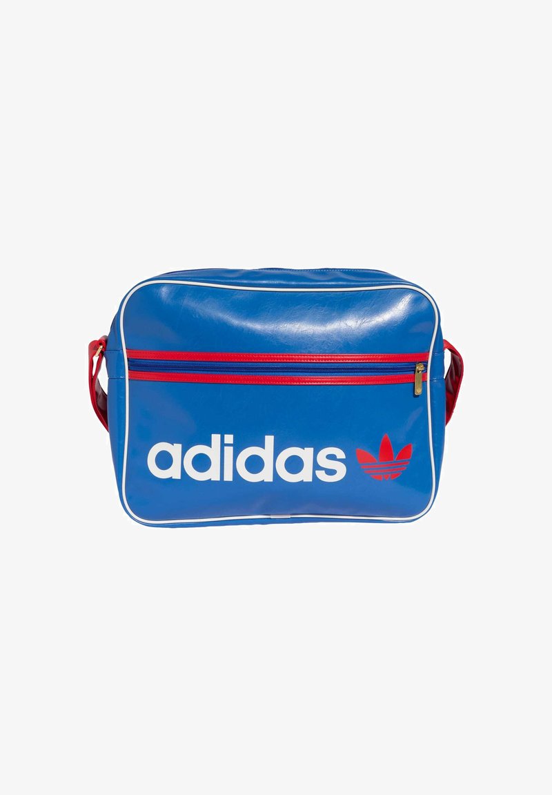 Borsa in vinile blu con logo "adidas" bianco e dettagli rossi, dotata di una tasca frontale con cerniera e bordi con piping bianco.