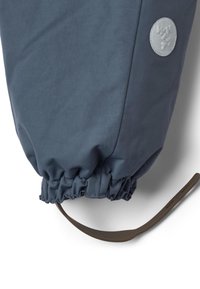 Sötétkék kültéri kabátujj elasztikus mandzsettával, kör alakú logópárnával és a mandzsetta mellett egy barna állítható pánttal.