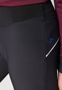 Fekete sport leggings sima textúrával, kék logóval és fehér díszcsíkkal az oldalon. Magas derék kialakítás.