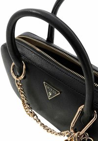 Sac à main noir texturé avec doubles poignées, accroche chaîne ton or, fermeture éclair et un logo en métal sur le devant.