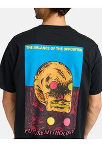 Black t-shirt featuring a colorful graphic print of a skull with red, yellow, and pink accents, and the text "THE BALANCE OF THE OPPOSITES."