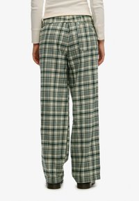 Pantalones de pierna ancha con estampado a cuadros en verde y beige, con cintura elástica y bolsillo trasero, confeccionados en un tejido suave y tejido.