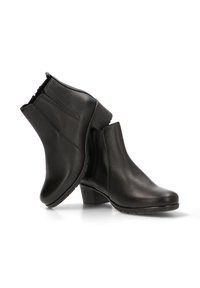 Botas de cuero negras hasta el tobillo con punta redondeada, un tacón bajo y apilado, y paneles laterales elásticos para un fácil uso. Textura suave con detalles mínimos.