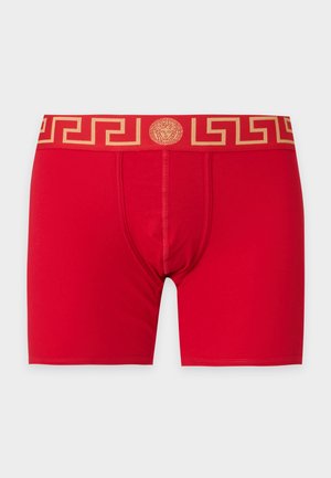 Boxers rouges pour homme avec une ceinture dorée à motif et un emblème central représentant la tête de Méduse.