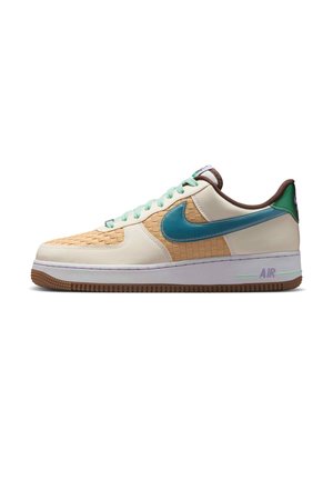 Zapatilla deportiva de perfil bajo con parte superior en crema, paneles tejidos beige, logo Nike en color teal, cordones menta, cuello marrón y suela blanca con dibujo marrón.