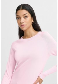 Heller rosa Pulli mit langen Ärmeln und Rundhalsausschnitt, der eine glatte Textur und feine Rippdetails an den Bündchen und dem Saum aufweist.