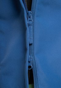 Blauer Stoff mit einer glatten Textur und einem Reißverschluss in der Mitte. Der Reißverschlussgriff ist blau und in das Design des Stoffes integriert.