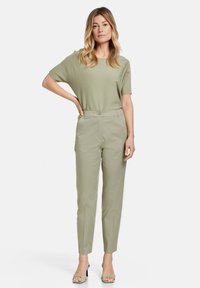Light green, relaxed-fit top paired with light green, tapered trousers. Smooth fabric with minimal detailing and a subtle sheen. Simple design.