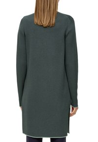 Robe longue à manches longues verte foncée, texture tricotée, col rond, fentes latérales à l'ourlet et coupe ajustée.
