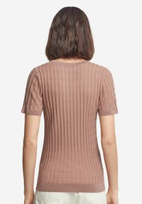 Kortärmad, ribbad stickad topp i dammig ros. Har rund halsringning och texturerad yta med vertikala linjer; mjukt, lätt material.