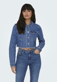 Kratka modra denim jakna z dolgimi rokavi, dvema žepoma na prsih in sprednjimi gumbi. Ima raztrgan rob in teksturirano površino tkanine.