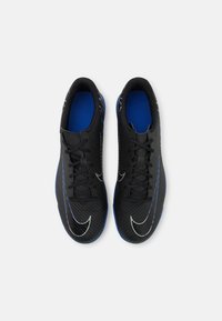 Botas deportivas negras con plantillas azules y logotipos de swoosh blancos, vistas desde arriba sobre un fondo blanco.