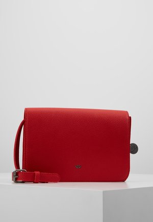 Petit sac pochette en cuir rouge avec bracelet et boucle argentée, présenté sur une surface blanche sur fond gris.