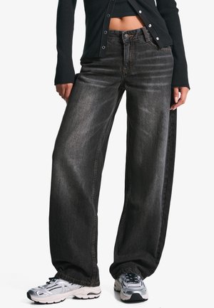 Wide-leg, dark gray jeans with a slightly faded texture, featuring a button and zipper closure, paired with metallic sneakers.